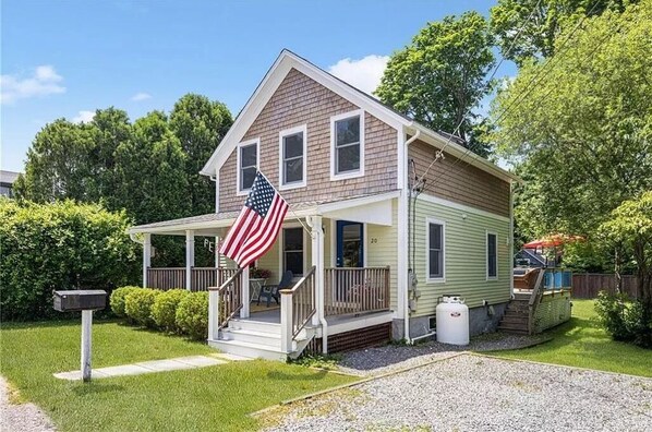 A two-story house with a porch, a mailbox, and an American flag.