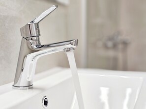 Ein modernes Waschbecken mit chromfarbenem Wasserhahn und klarem, fließendem Wasser.
