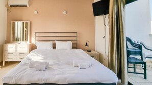 A hotel room with a large bed, a bedside table, a mirror, a wardrobe, and a view of the outside balcony. - Ben Yehouda Obsidian (Tel Aviv)