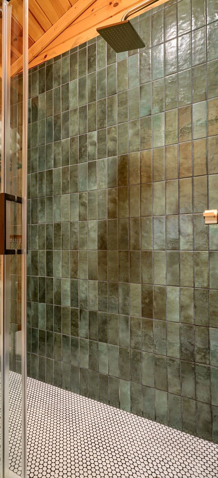 Un espace douche avec un mur et un sol carrelés, une pomme de douche et un plafond en bois.