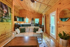 A cozy cabin interior with a living area, kitchen, and a dining space. - 5 Min Old Mans Cave & Falls | Hot Tub | Game Table (Logan)