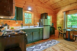 Una cucina in legno con un fornello, lavello, frigorifero e zona pranzo con tavolo e sedie.