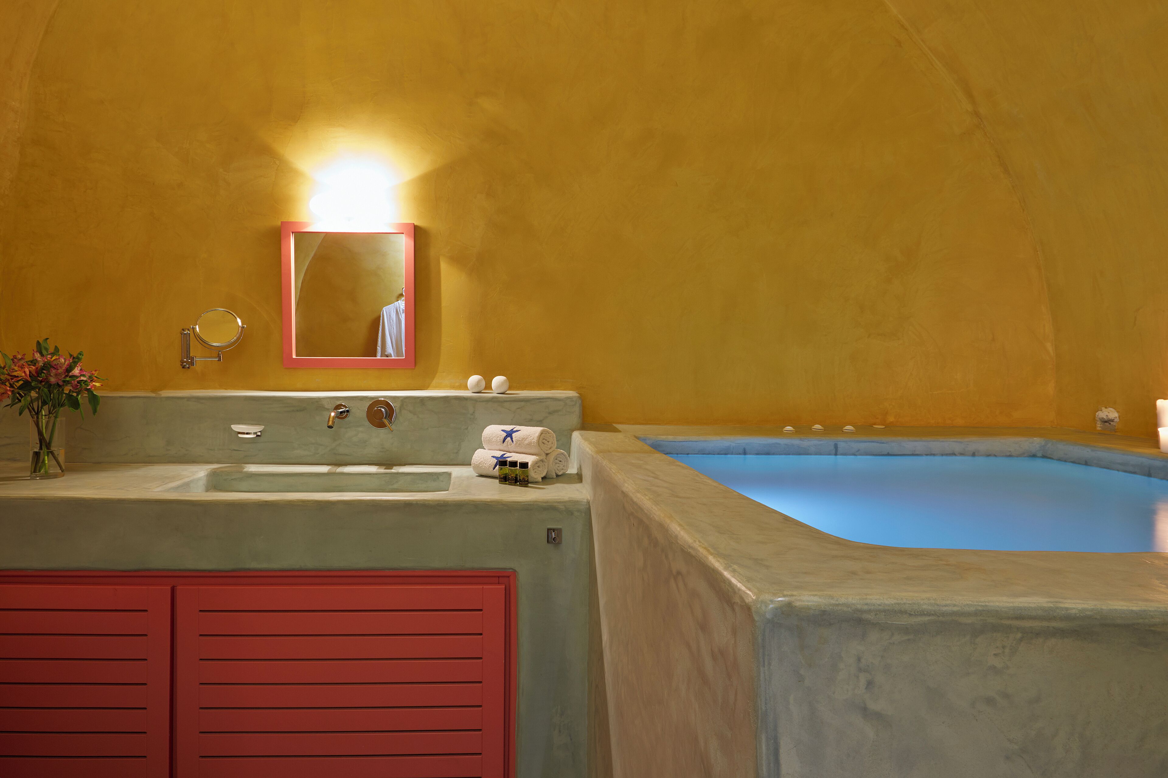 A bathroom with a sink, mirror, and bathtub.