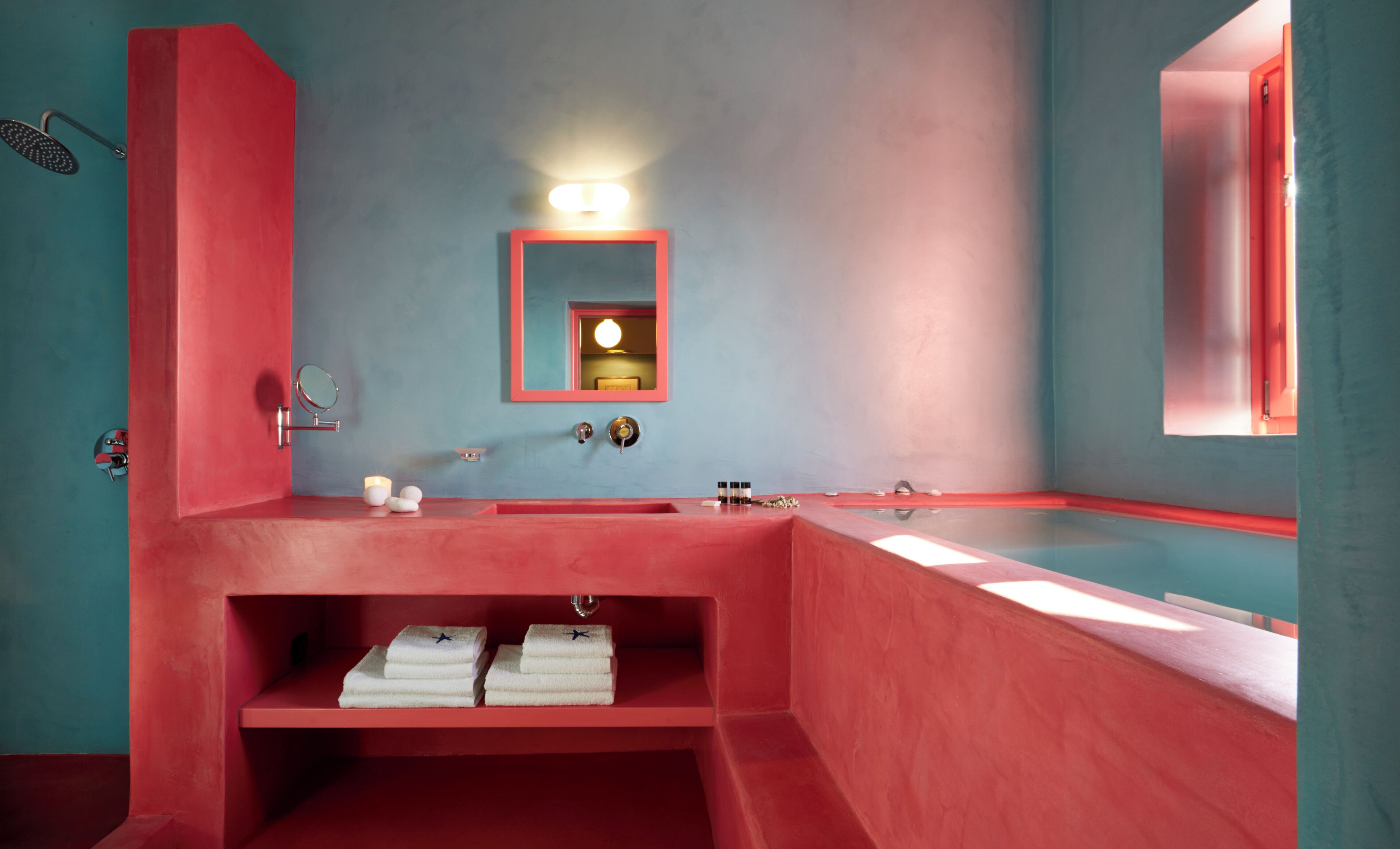 Une salle de bain avec un lavabo rouge, un miroir et une étagère avec des serviettes.