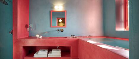 Une salle de bain avec un lavabo rouge, un miroir et une étagère avec des serviettes.