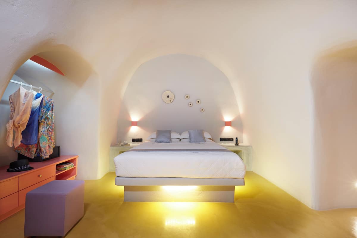 A modern bedroom with a white bed, a vanity with a mirror, and a small seating area.