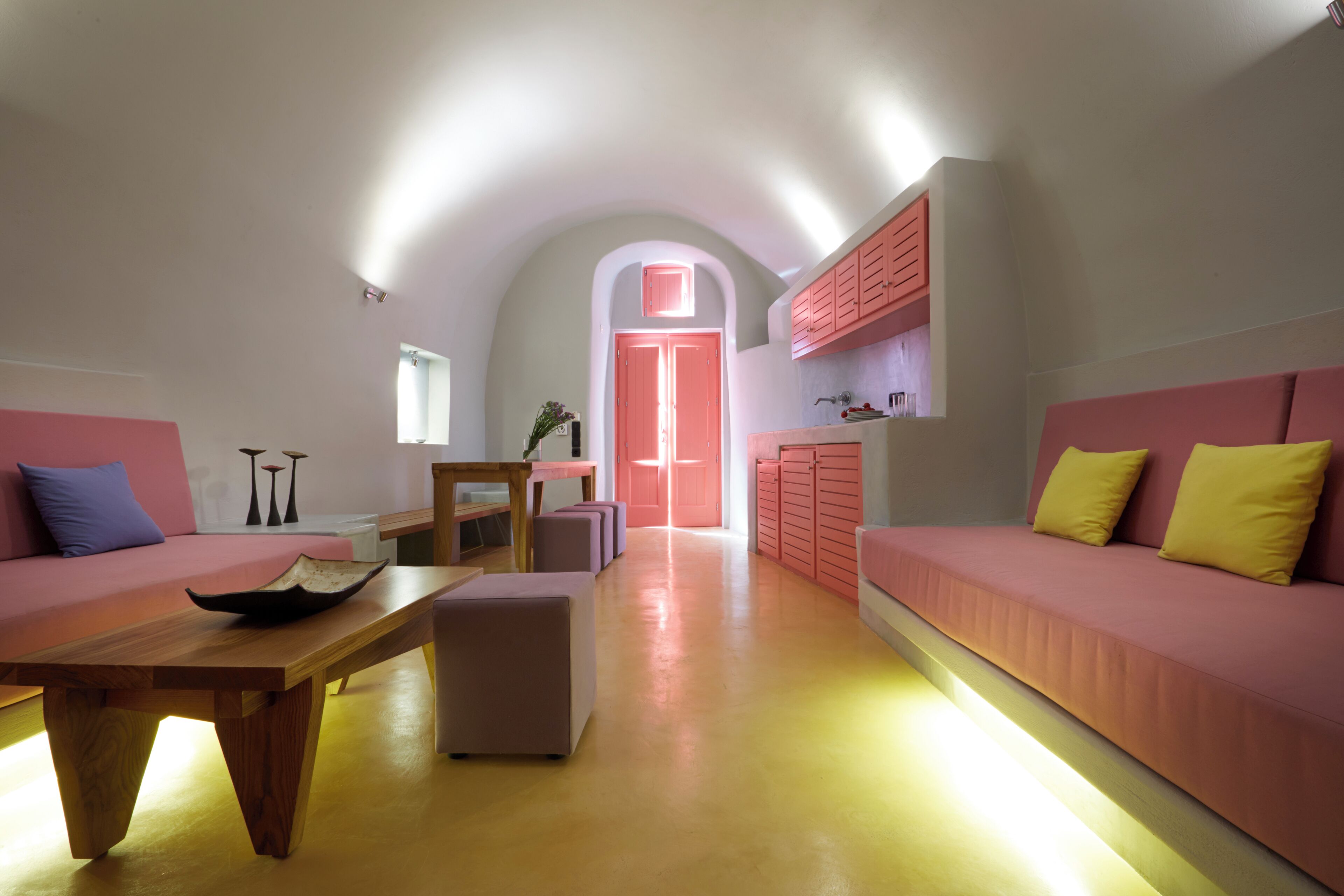 Un intérieur moderne avec une table en bois, des canapés roses et un coin cuisine.