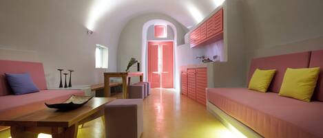 Un intérieur moderne avec une table en bois, des canapés roses et un coin cuisine.
