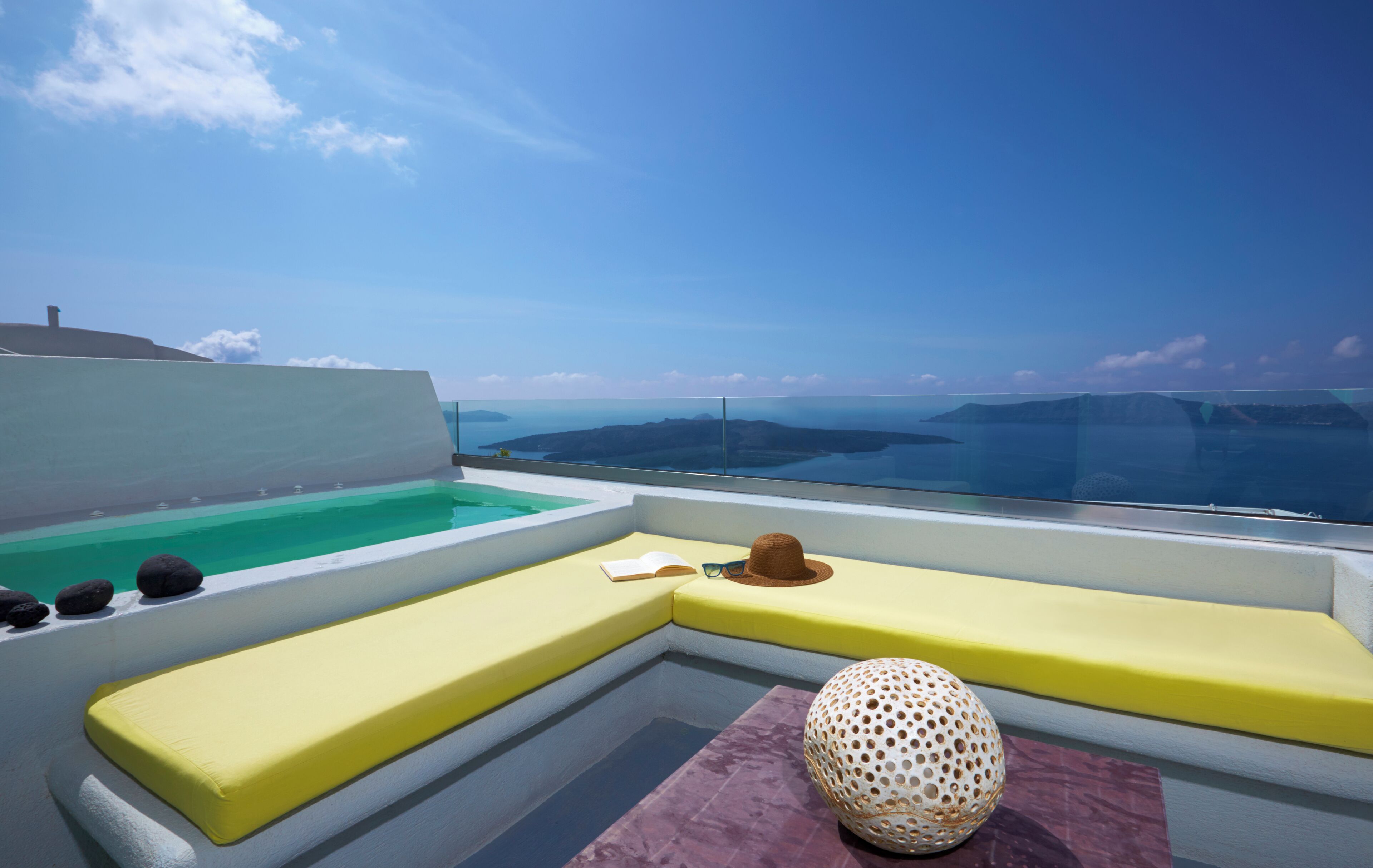 A modern outdoor seating area with a pool, a hat, and a book.