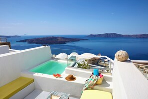 A rooftop terrace with a pool, seating areas, and a view of the sea and islands.