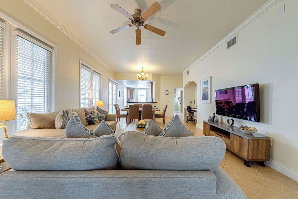 Un salon avec un canapé, un téléviseur et un ventilateur de plafond.