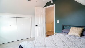 Une chambre à coucher comprenant un lit, une armoire et une porte donnant sur une autre pièce.