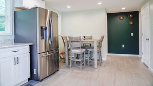 A modern kitchen with stainless steel appliances, a dining table with chairs, and a dark accent wall. - Charming 3-bedroom house in enjoyable Endwell (Endicott)