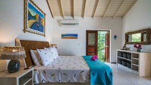 Une chambre à coucher comprenant un lit, une table de chevet, une lampe, un tableau, une étagère avec des boîtes de rangement et une fenêtre avec des volets.