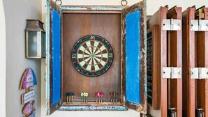Une cible de fléchettes fixée à un mur rustique, encadrée de bleu et entourée de portes en bois.