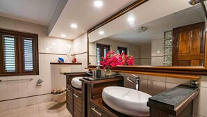 Une salle de bain moderne avec deux lavabos, un grand miroir et un meuble-lavabo doté d’un plan de travail en bois.