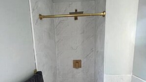 Une salle de bain avec une douche, un porte-serviettes et des toilettes.