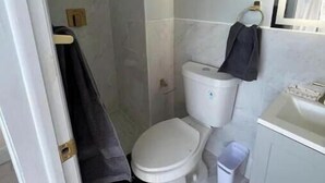 Une petite salle de bain comprenant des toilettes, un lavabo et un espace douche.
