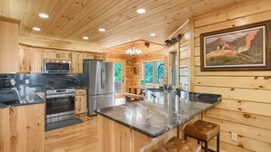 A modern kitchen with wooden walls, stainless steel appliances, and a marble countertop. - Eagle's Escape - Mountain top lodge with spectacular views (Huntingdon)