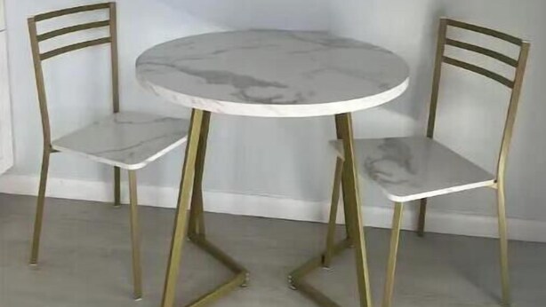 Een ronde tafel met twee stoelen, allebei met een oppervlak dat op marmer lijkt en gouden poten.