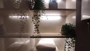 Une salle de bain avec un porte-serviettes, des étagères et des plantes suspendues.