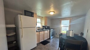 A compact kitchen with a refrigerator, stove, microwave, and wooden cabinets.