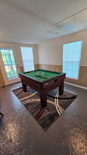 Relax in a spacious room with a pool table and large window, surrounded by comfortable seating and dark-toned accents.