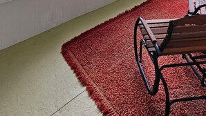 Una habitación con ventanas amplias, un tapete rojo y un banco de madera.