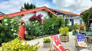A colorful building with a red and white facade, surrounded by lush greenery and flowering plants.