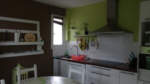 A kitchen with white cabinets, a green wall, a window, and a sink.