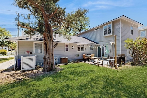 A two-story house with a front porch, a tree, and a well-maintained lawn.