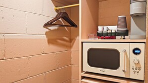 A compact kitchenette with a microwave, coffee maker, and a small refrigerator. - Mid-Century Themed Hotel Room in Fayetteville, AR - The Clementine on College #8 (Fayetteville)