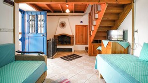 Una habitación acogedora con chimenea, vigas de madera, una puerta azul y dos camas con ropa de cama a juego.
