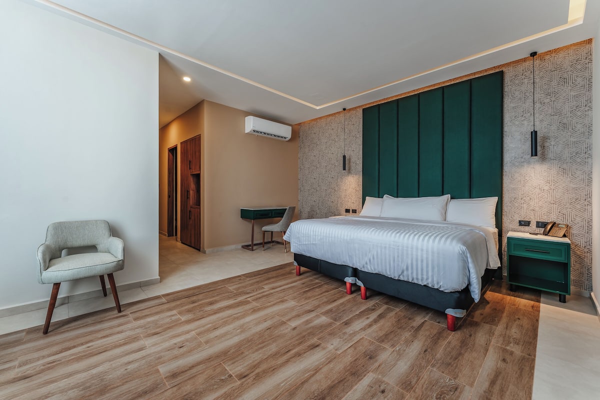 Une chambre à coucher moderne avec un grand lit, une chaise, un bureau et une table de chevet.