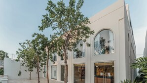 A modern building with a courtyard featuring trees, large windows, and a visible restaurant. - Hotel Chariot (Mérida)
