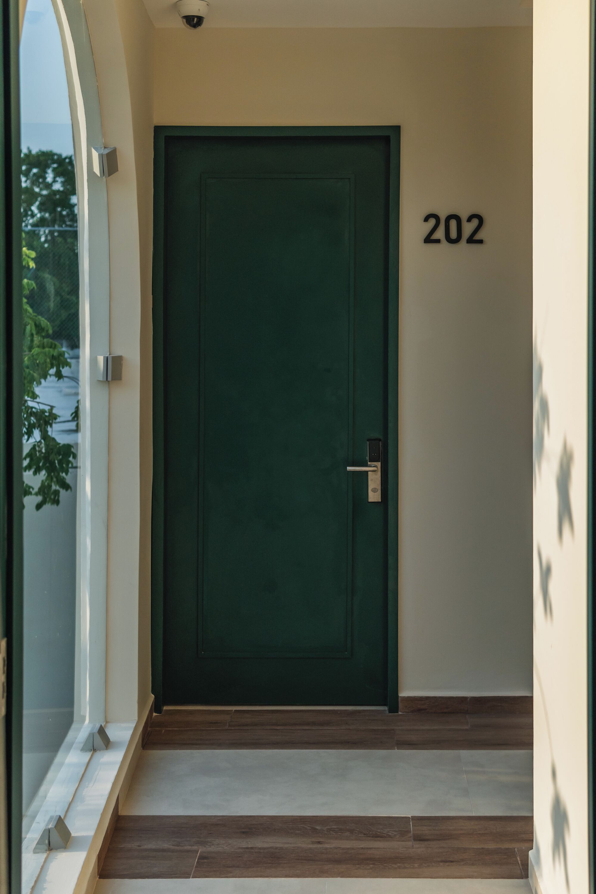 Una puerta verde con el número "202" en la pared de al lado.