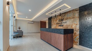 A reception desk with a marble wall and a wooden panel design. - Hotel Chariot (Mérida)