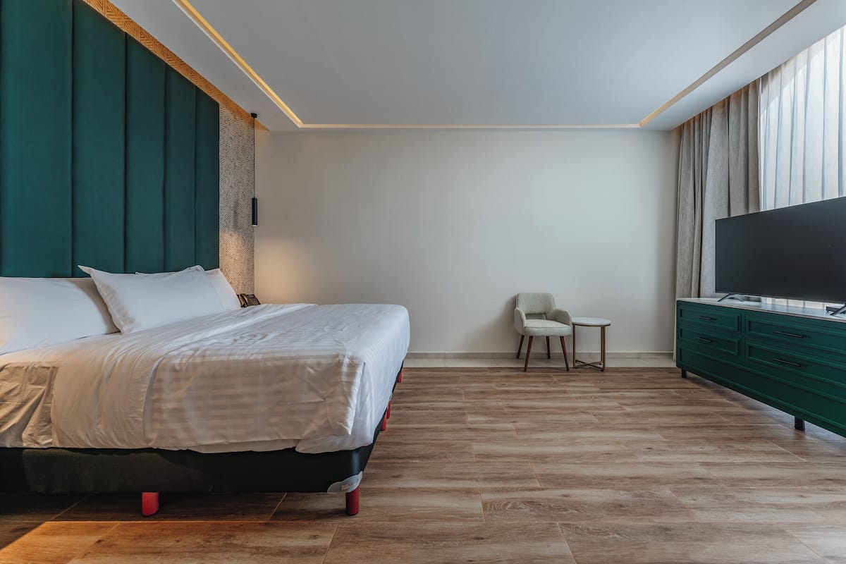 Une chambre moderne avec un lit, une télévision, une petite table et une chaise.