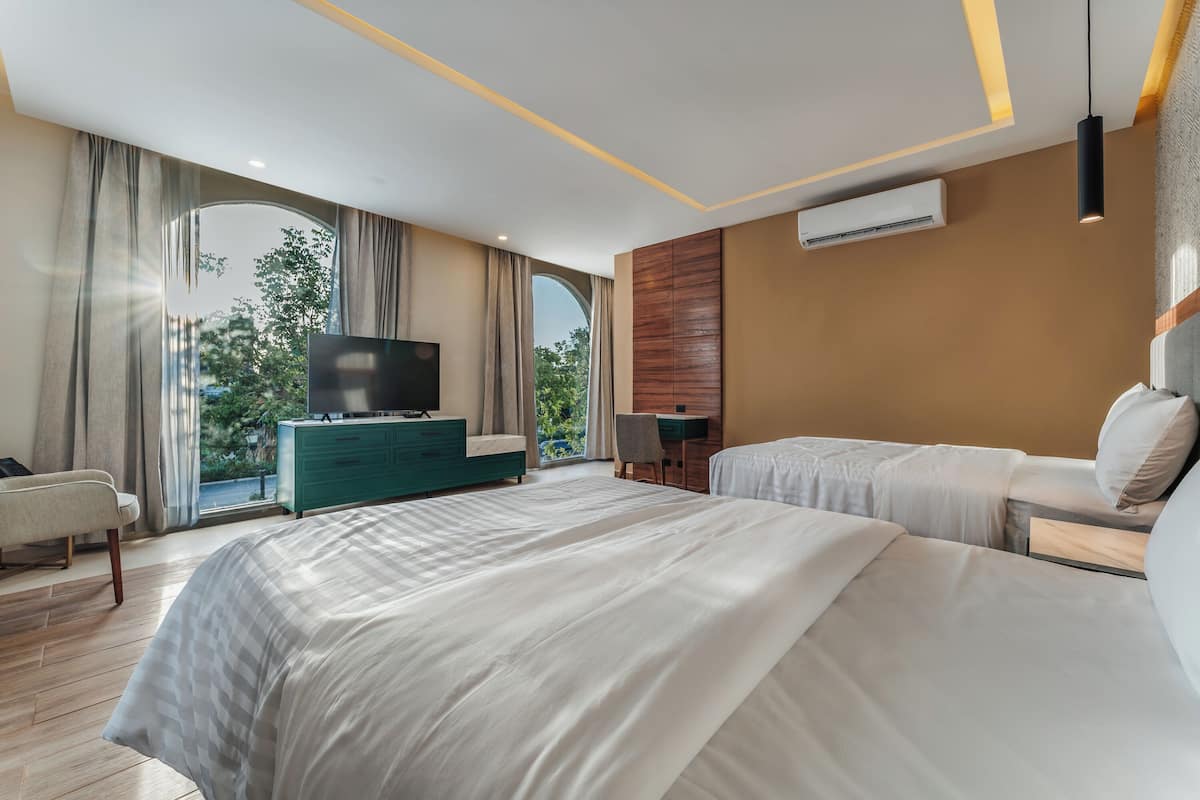 Une chambre d’hôtel moderne dotée d’un grand lit, d’une télévision, d’un bureau et offrant une vue sur l’extérieur.
