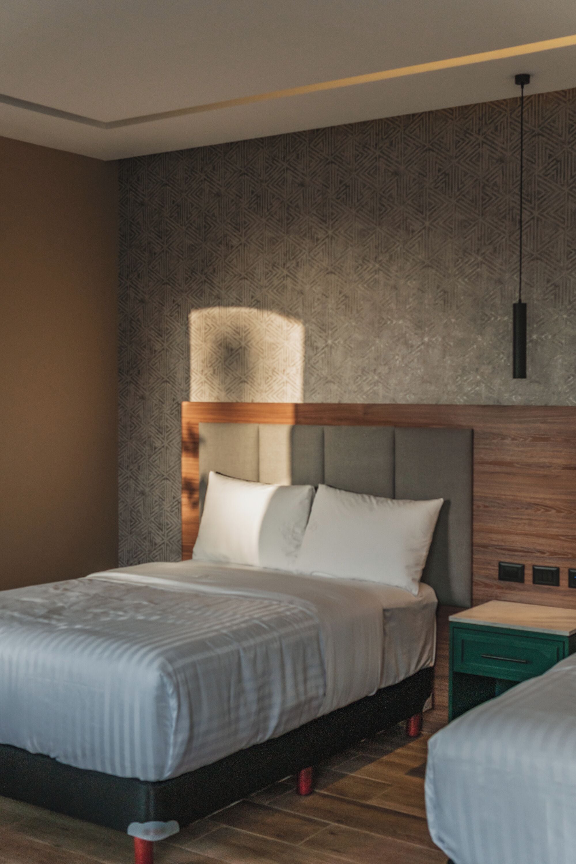 Une chambre d’hôtel moderne avec un grand lit, une tête de lit en bois et un mur orné d’un motif.