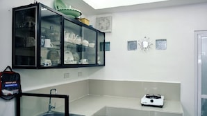 A kitchen with a glass-fronted cabinet, a sink, a stove, and a bag labeled "MEDIPLAST EMERGENCY KIT" on the wall. - Ocean View Paradise in Puerto Galera (Puerto Galera)