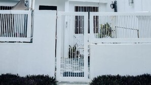A white two-story building with a gated entrance, satellite dish, and multiple air conditioning units. - Ocean View Paradise in Puerto Galera (Puerto Galera)