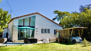 Et moderne hus med to etager, en patio, en carport og et overdækket udendørs siddeområde.