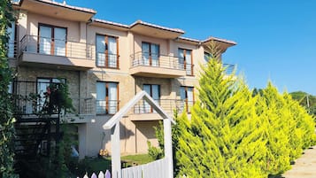 Stunning multi-story building with spacious balconies, large windows, and a flat roof, set amidst a beautifully maintained garden.