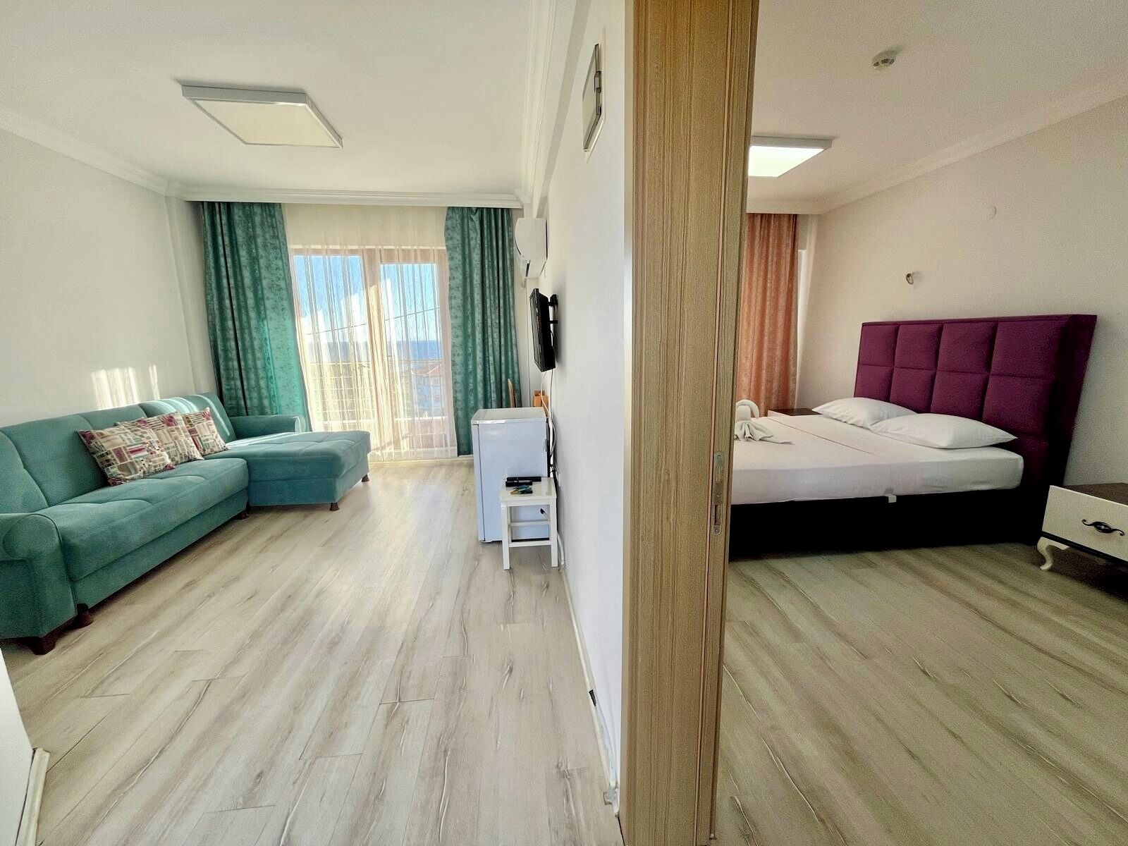 Una habitación con una cama, un sofá, una mesita y un televisor.