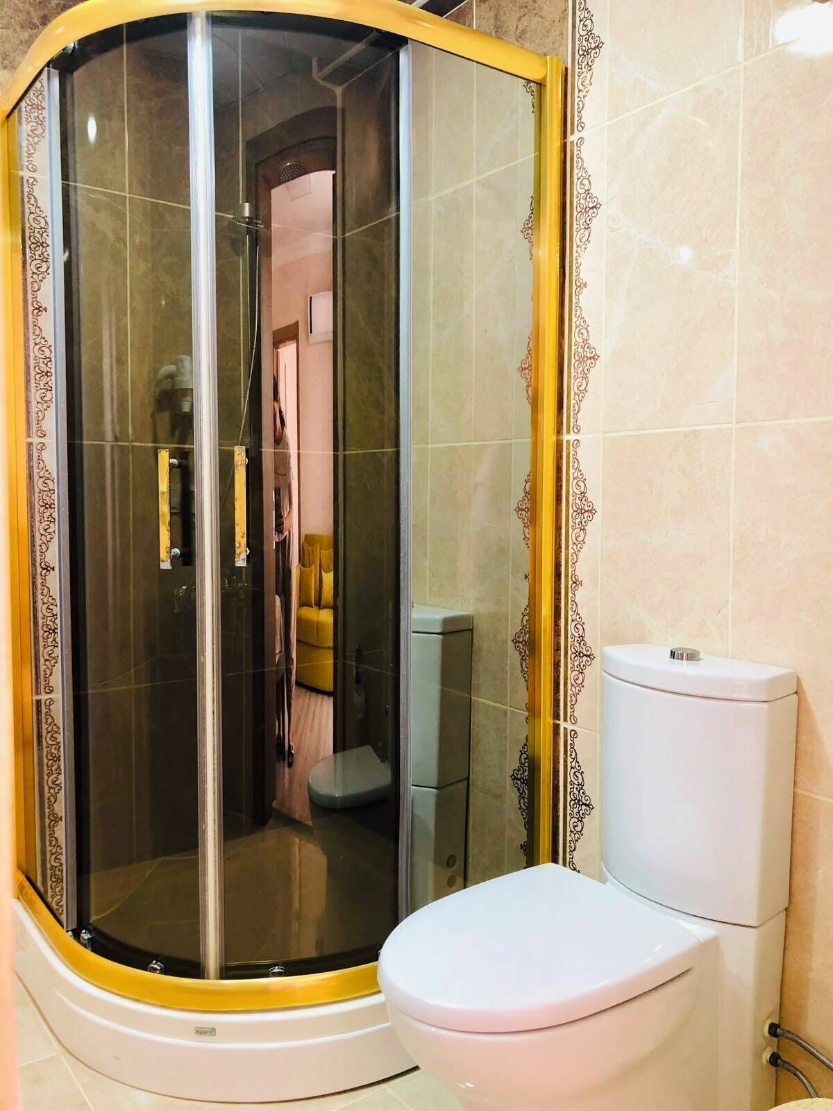 A corner shower enclosure with a glass door, a toilet, and a sink.