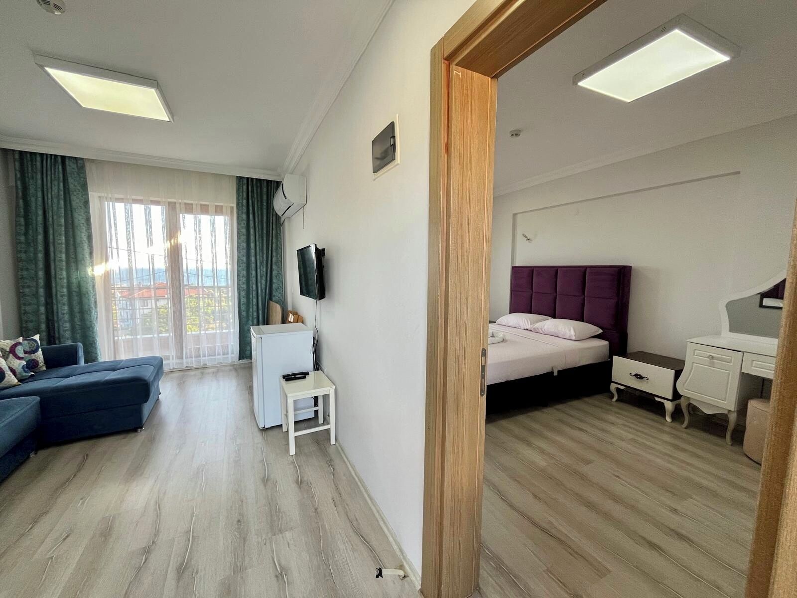 A modern hotel room with a sofa, a bed, a desk, and a television.