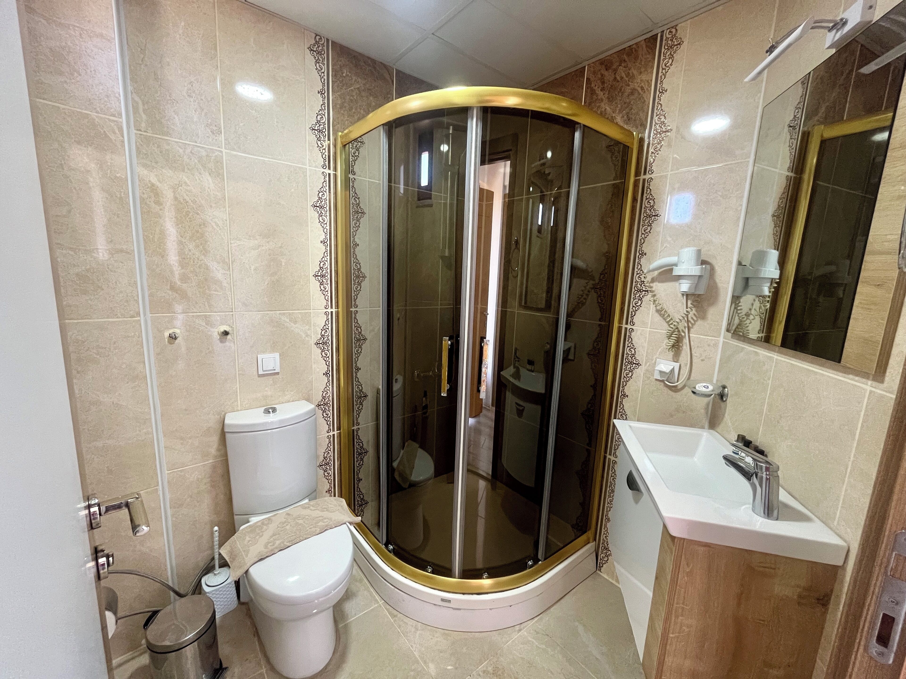 Un baño con ducha envuelta en vidrio, un inodoro y un lavabo.