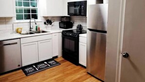 A modern kitchen with white cabinets, a stainless steel refrigerator, a black stove, a microwave, and a sink. - Spacious Douglasville/Lithia Springs Retreat: 5BR, 3BA for Families or Business (Lithia Springs)