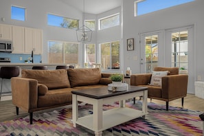 A modern living room with a brown leather sofa, a white coffee table, and a colorful rug. - Spacious Retreat w/ Free Heated Pool – Close to Stadium & Ballparks! (Peoria)